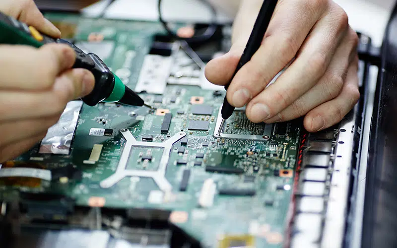 AURA-solder-PCB-AdobeStock_136939755-800×500 Close up of a persons hands using a solder iron on a PCB